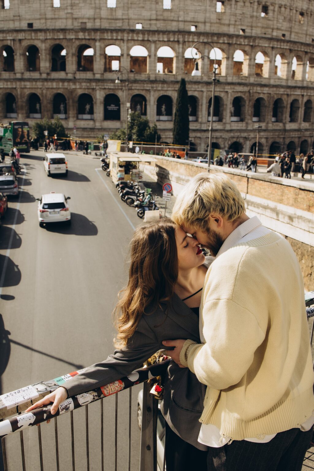 Couple kissing on the terrace above the traffic with the Colosseum behind