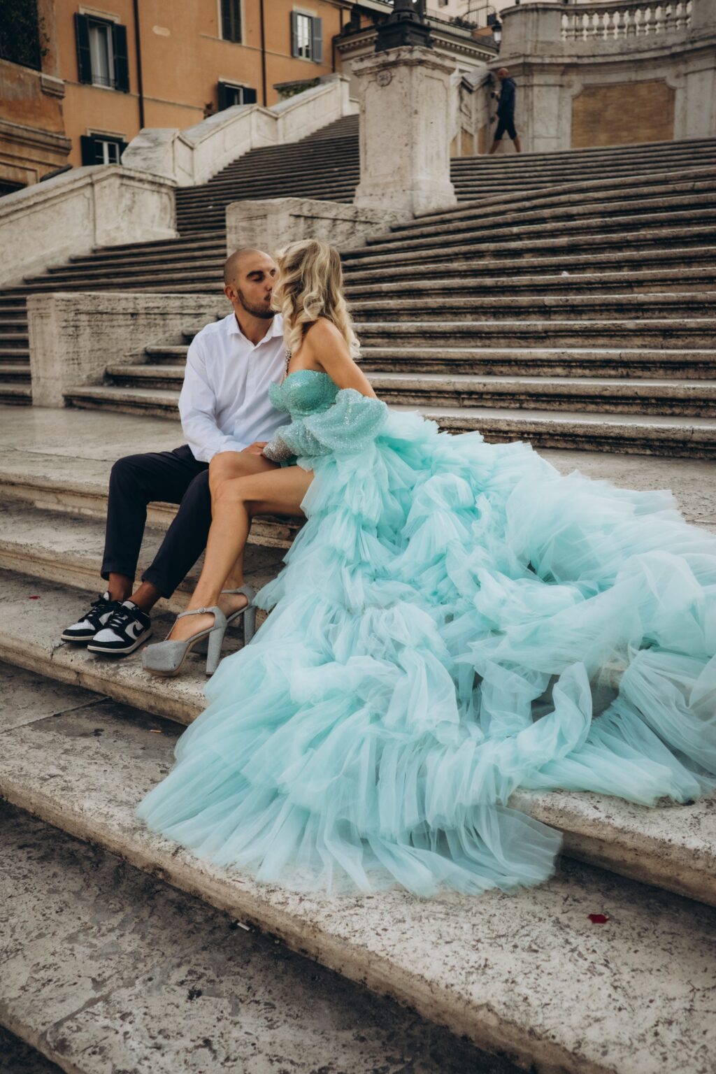 Couple sitting on the Spanish Steps, her mint tulle train spread across the stairs