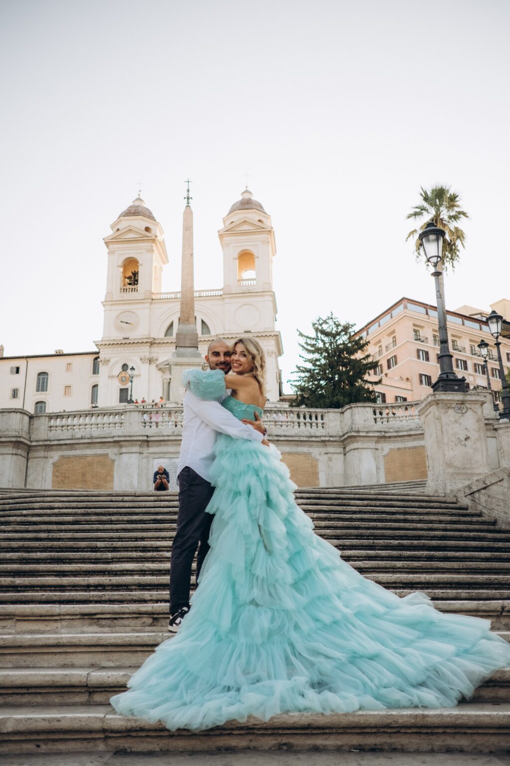 Couple embracing on the Spanish Steps, her mint flying dress trailing down the stairs below Trinità dei Monti