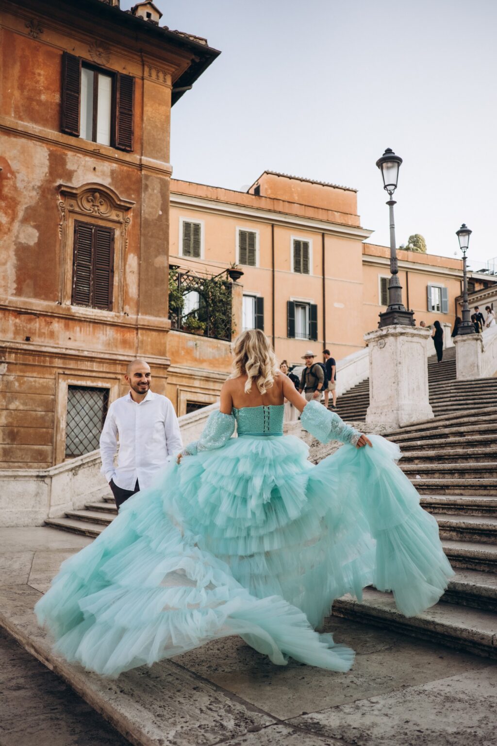 Woman lifting the mint tulle train of her flying dress on the Spanish Steps