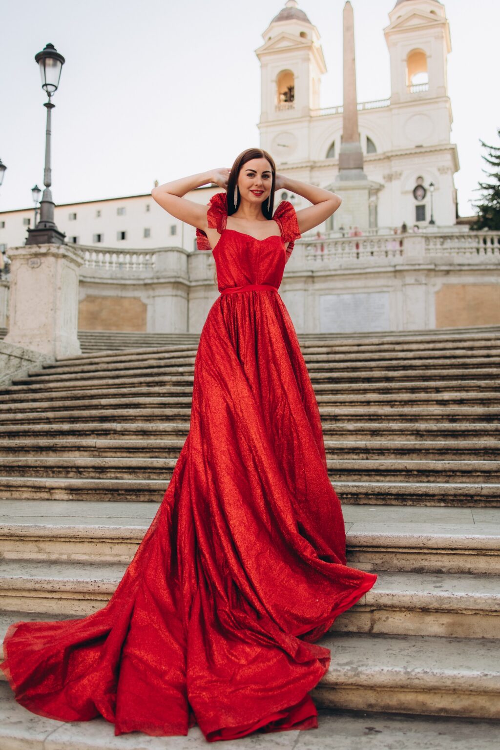 Red sparkling gown on the Spanish Steps with Trinità dei Monti behind