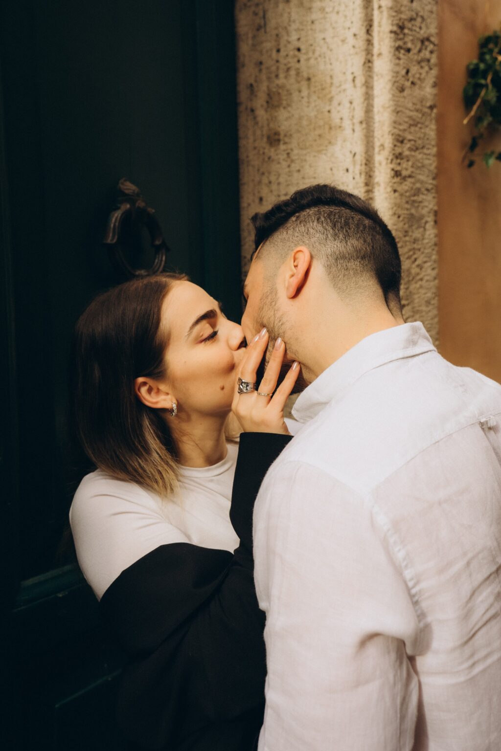 A kiss in a Roman doorway, showing the engagement ring