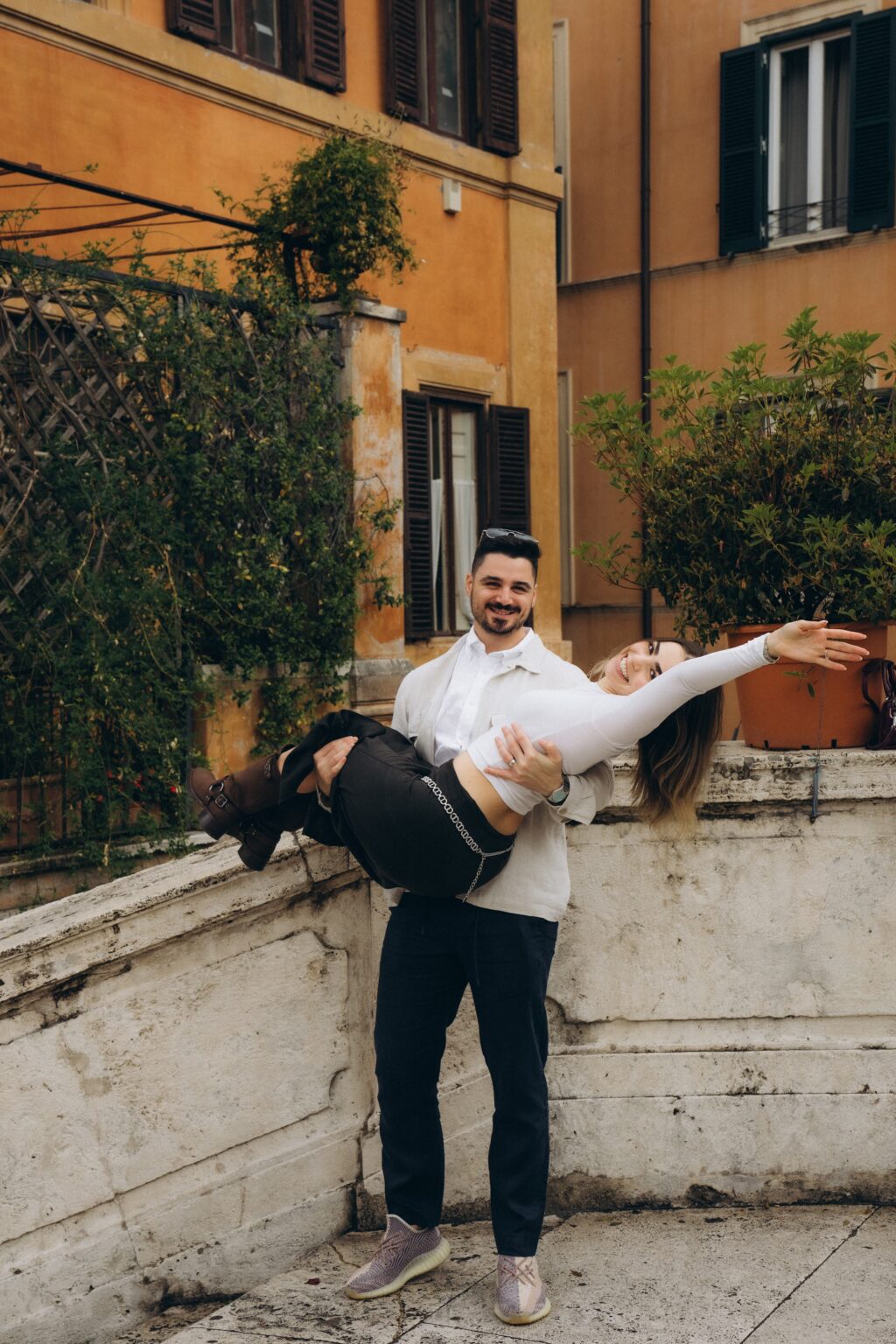 He lifts her in front of an orange Roman palazzo
