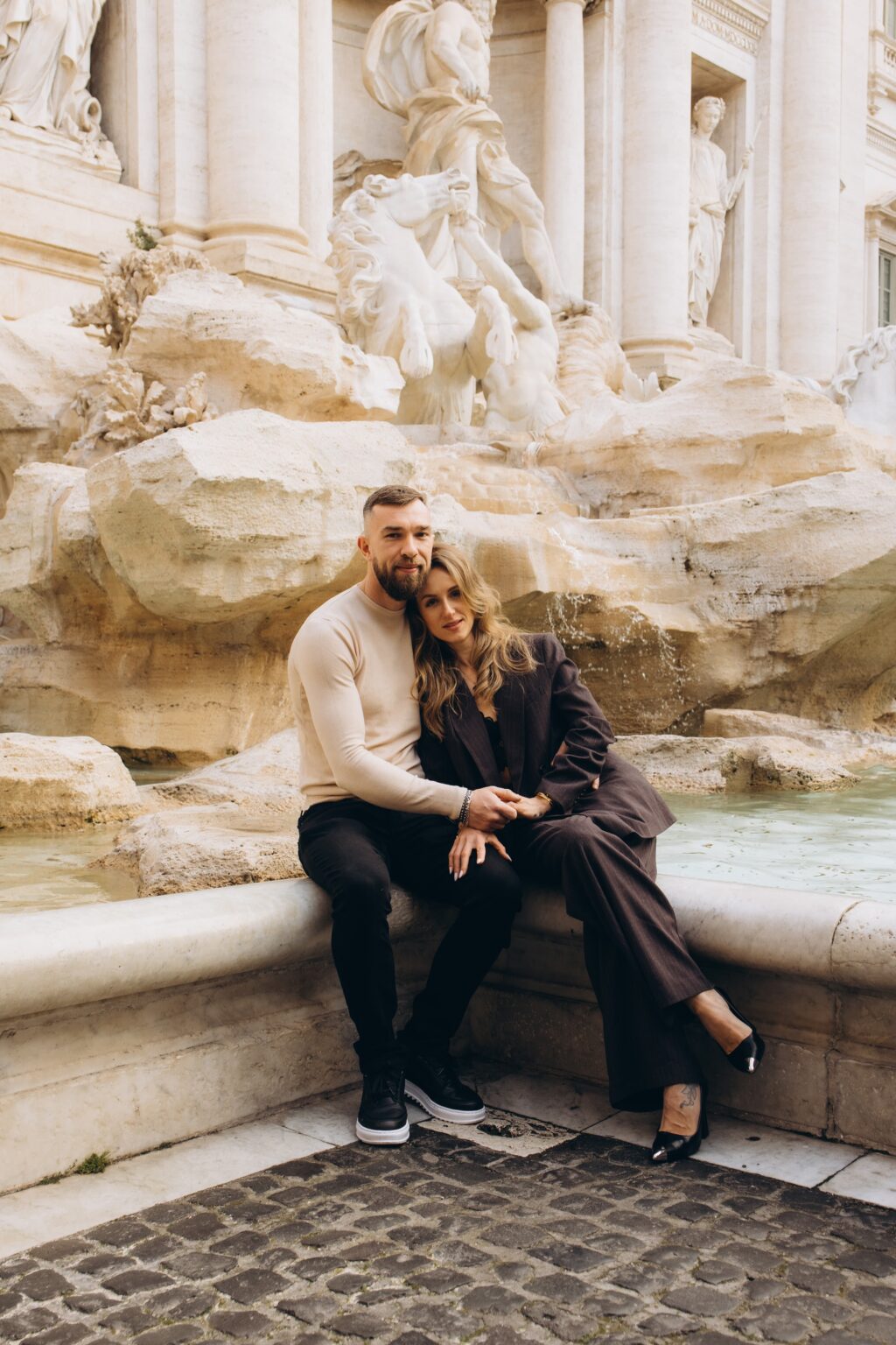 Couple sitting on the rocks of the Trevi Fountain