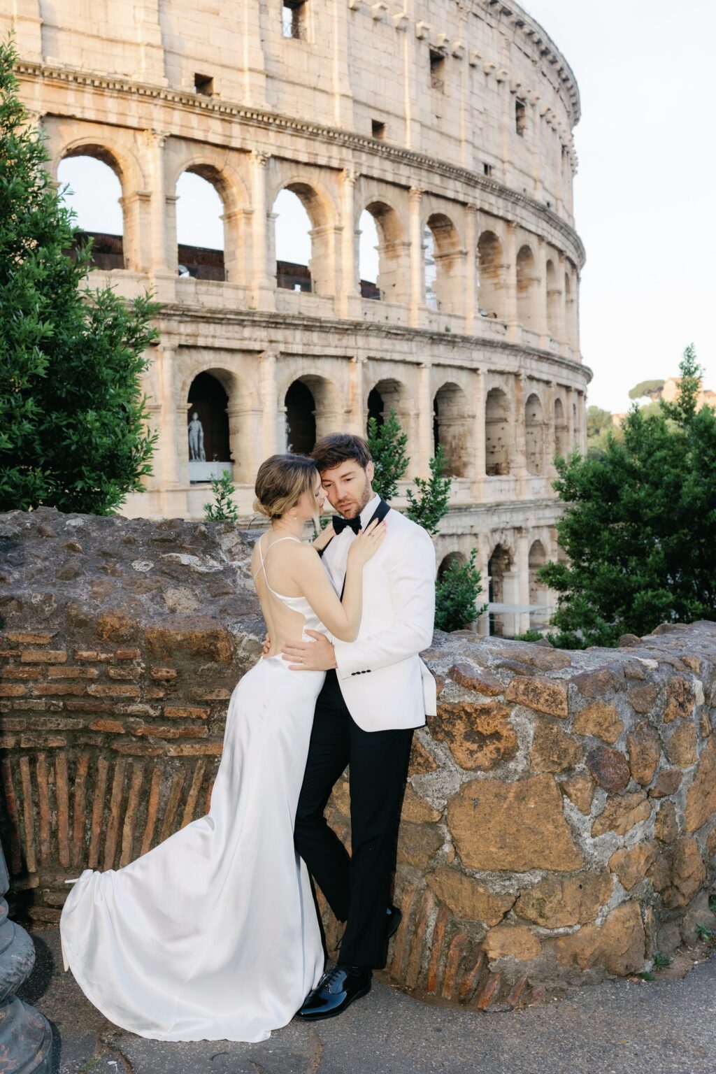 Newlyweds leaning on an ancient wall by the Colosseum