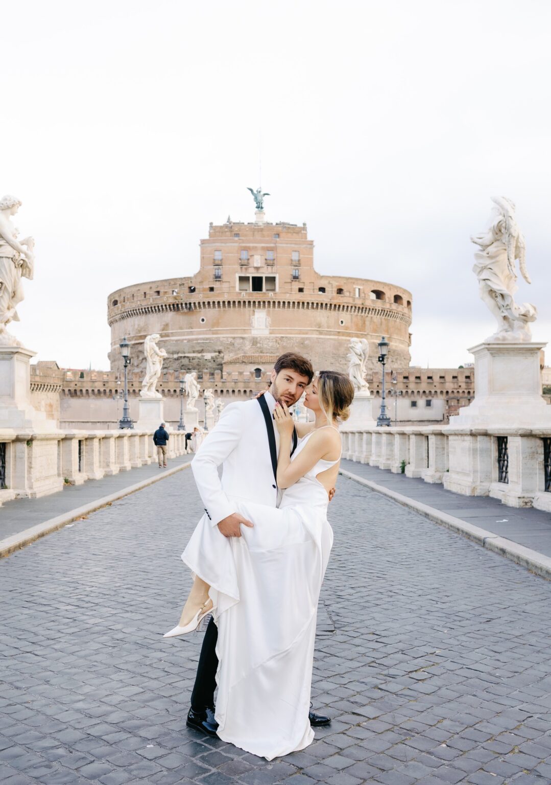Groom lifting the bride on Ponte Sant'Angelo with the castle behind