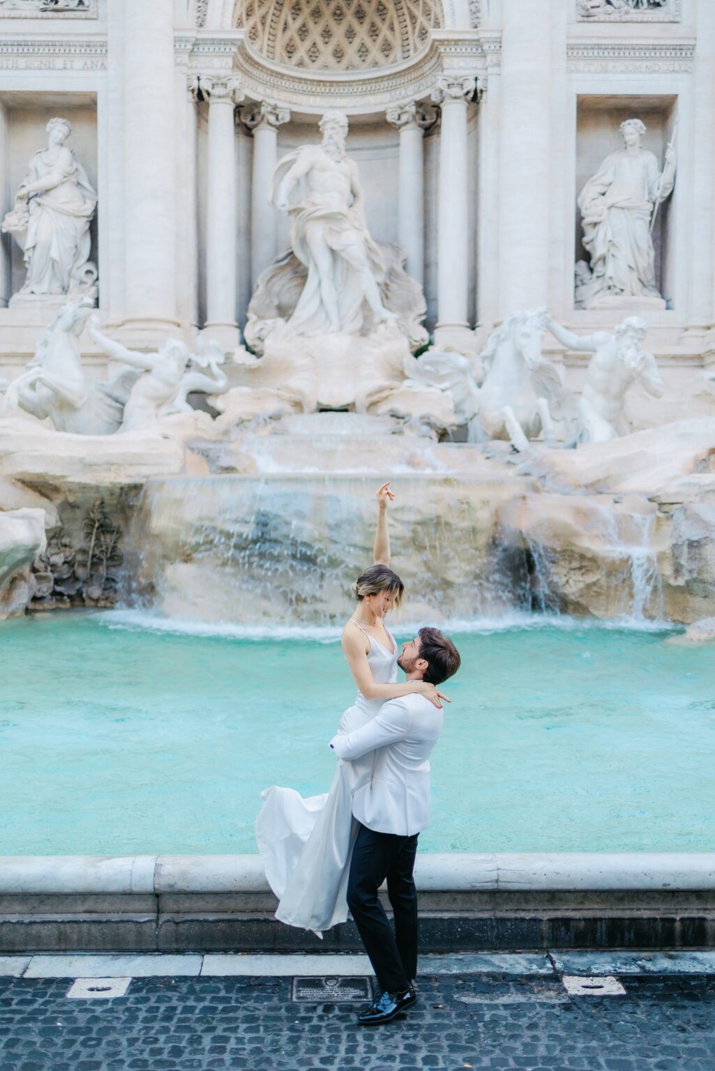Groom lifting the bride in front of the Trevi Fountain at 7am