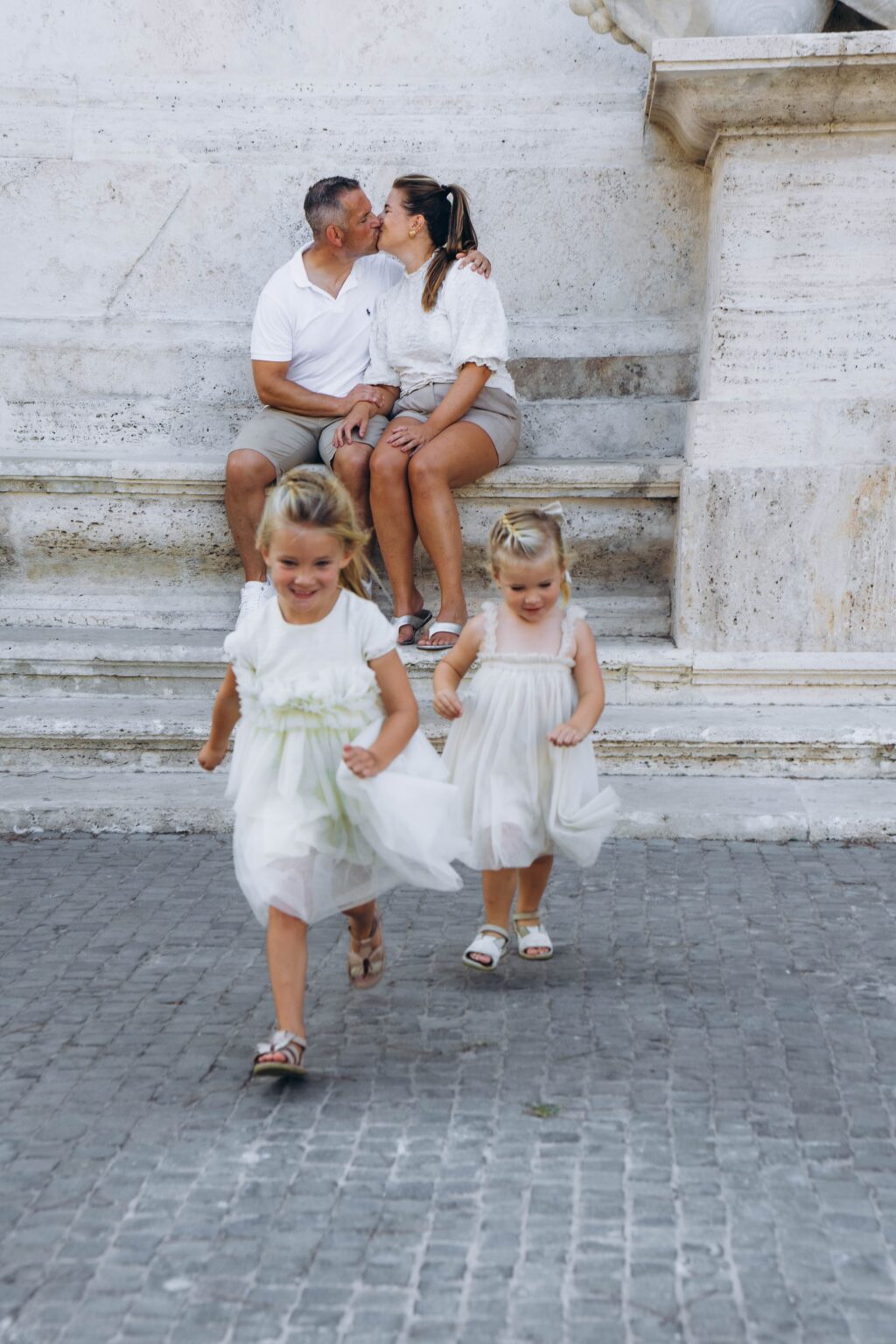 Girls running down the Capitoline steps while their parents kiss
