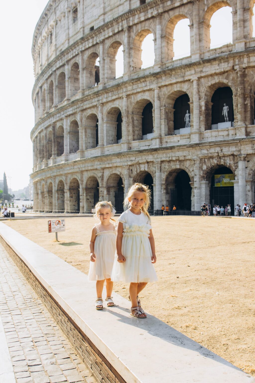 Two little sisters walking in front of the Colosseum