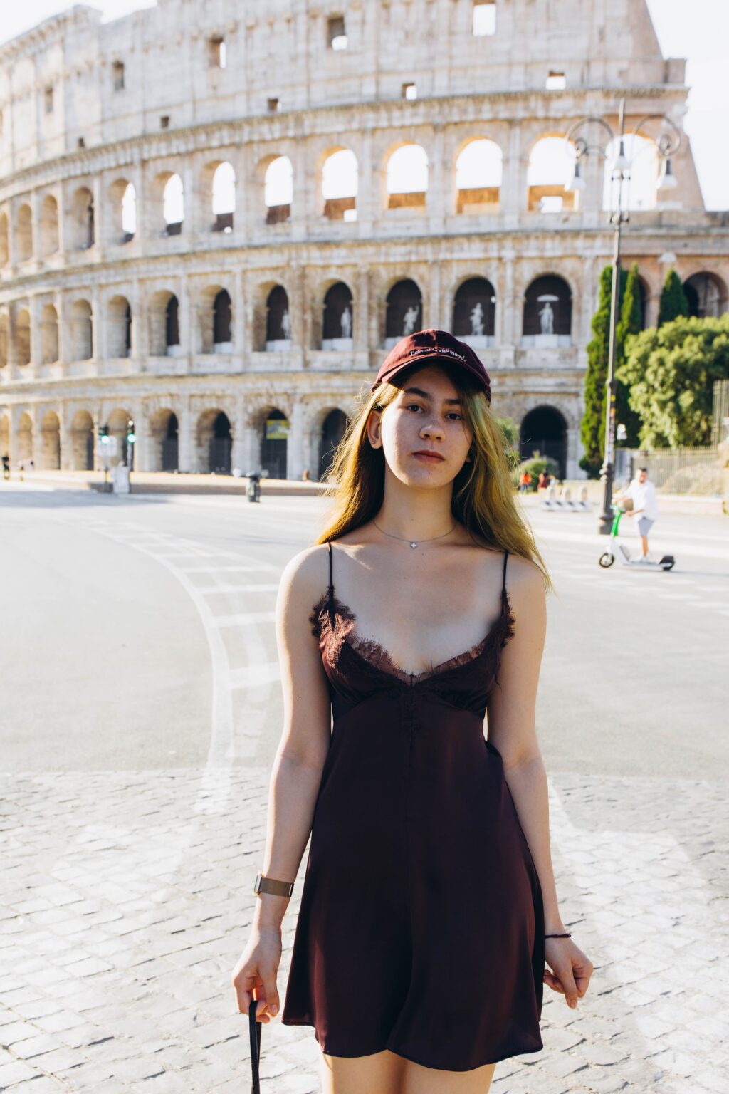 Portrait in a black slip dress on the road by the Colosseum, June morning