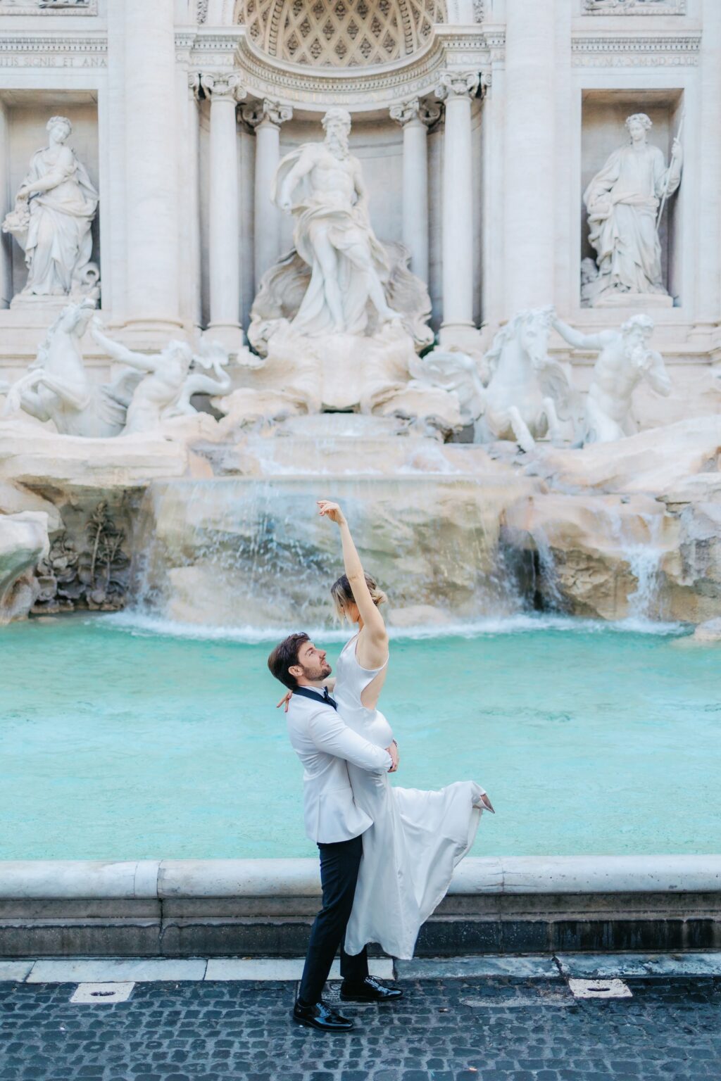 He lifts her in front of the Trevi Fountain just after 7am in May