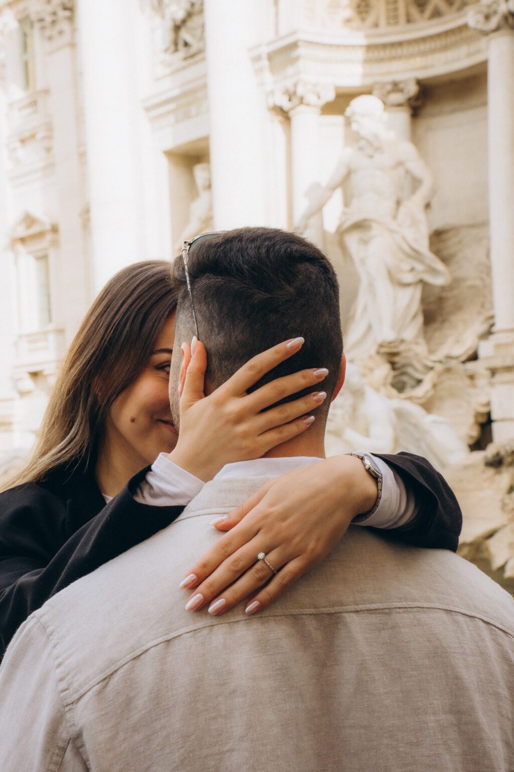 Showing the engagement ring in an embrace at the Trevi Fountain