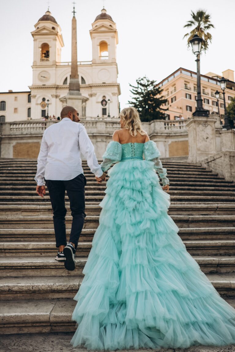 Couple climbing the Spanish Steps towards Trinità dei Monti, her mint tulle train on the stairs
