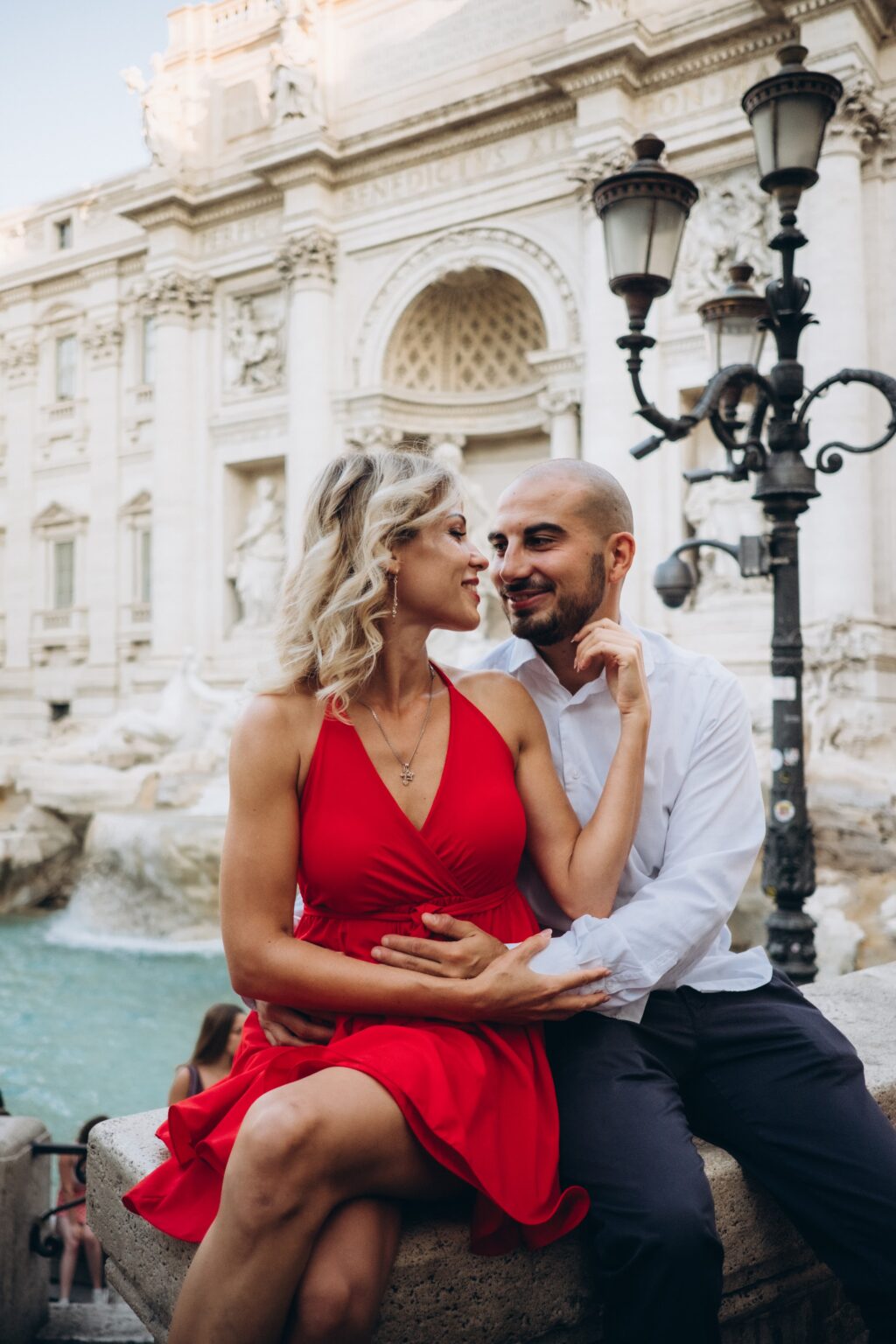 Couple in a red dress sitting at the Trevi Fountain