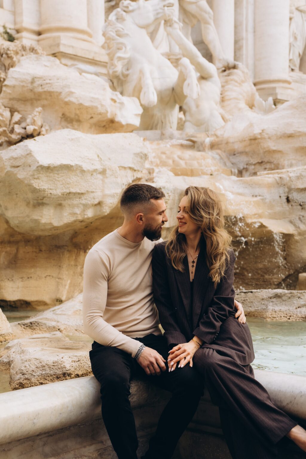 Couple sitting on the rocks of the Trevi Fountain