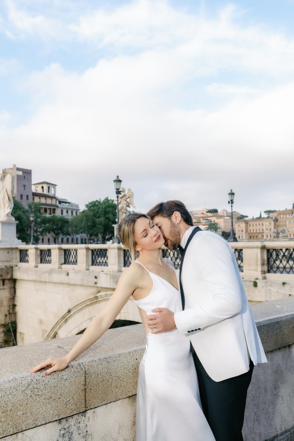 Bride and groom kissing by the Tiber near Ponte Sant'Angelo