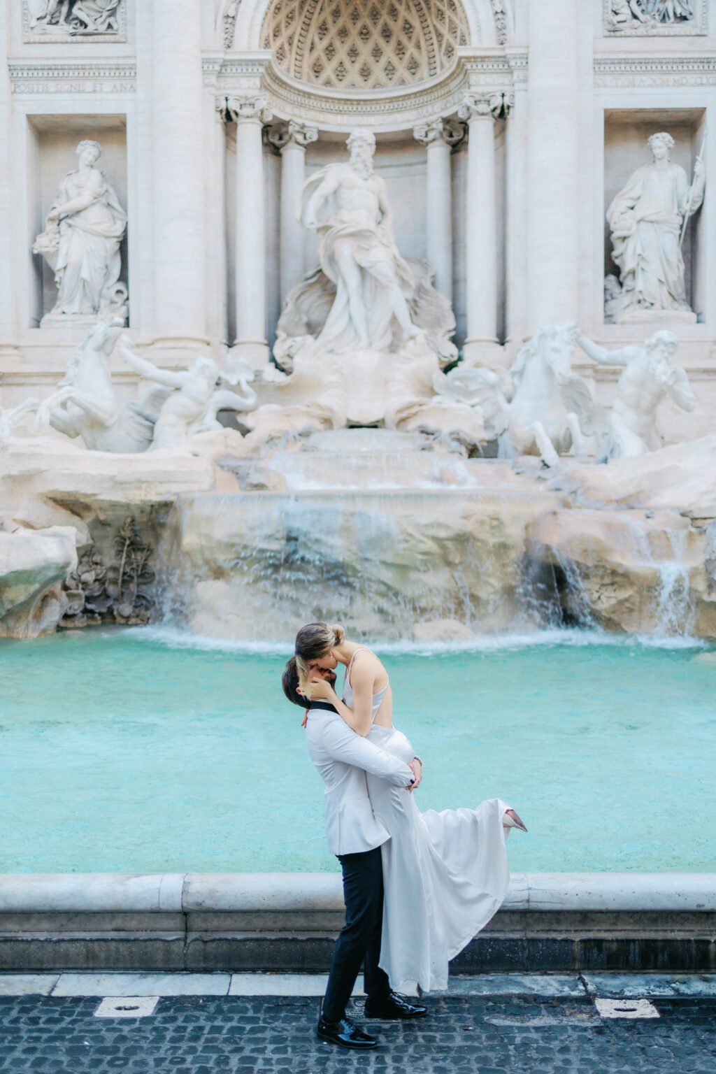 Groom lifting the bride at the Trevi Fountain, her dress in the air