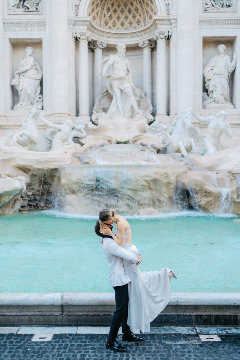 Groom lifting the bride at the Trevi Fountain, her dress in the air